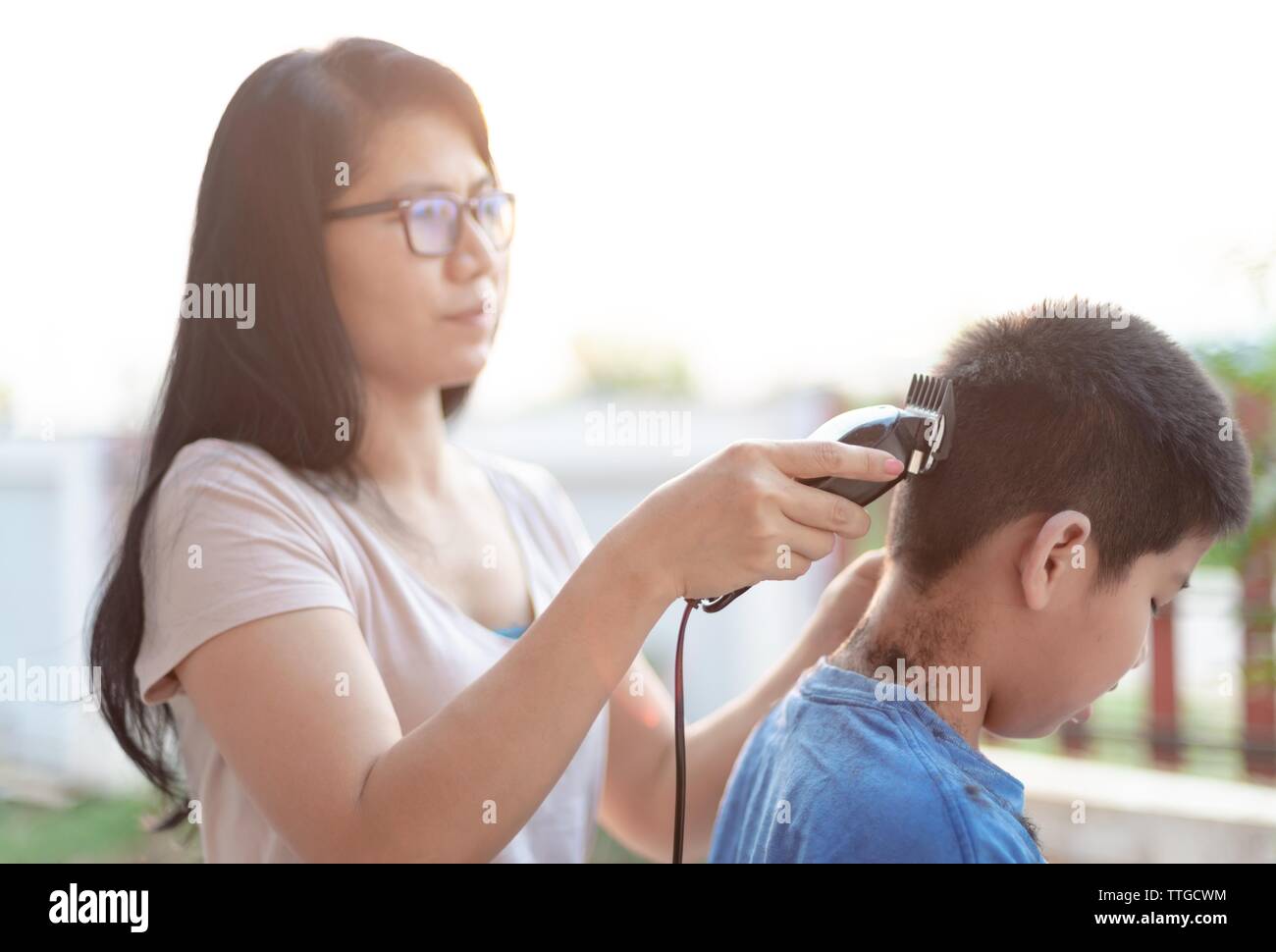 Mutter schneiden Haare für Sohn Stockfoto