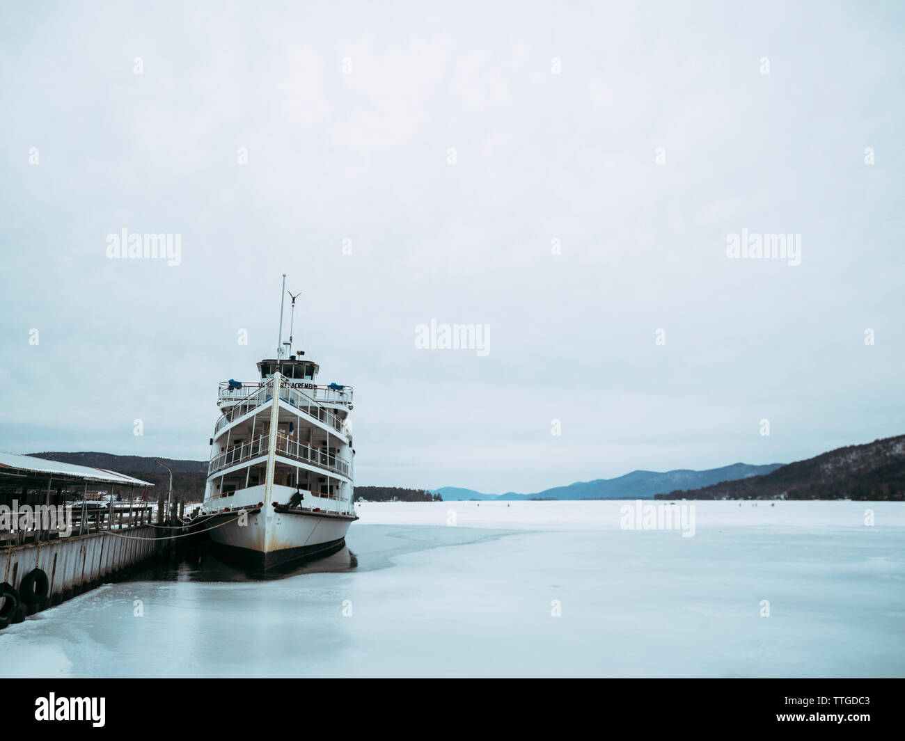 Boot vertäut im Hafen auf dem zugefrorenen See George gegen bewölkter Himmel Stockfoto