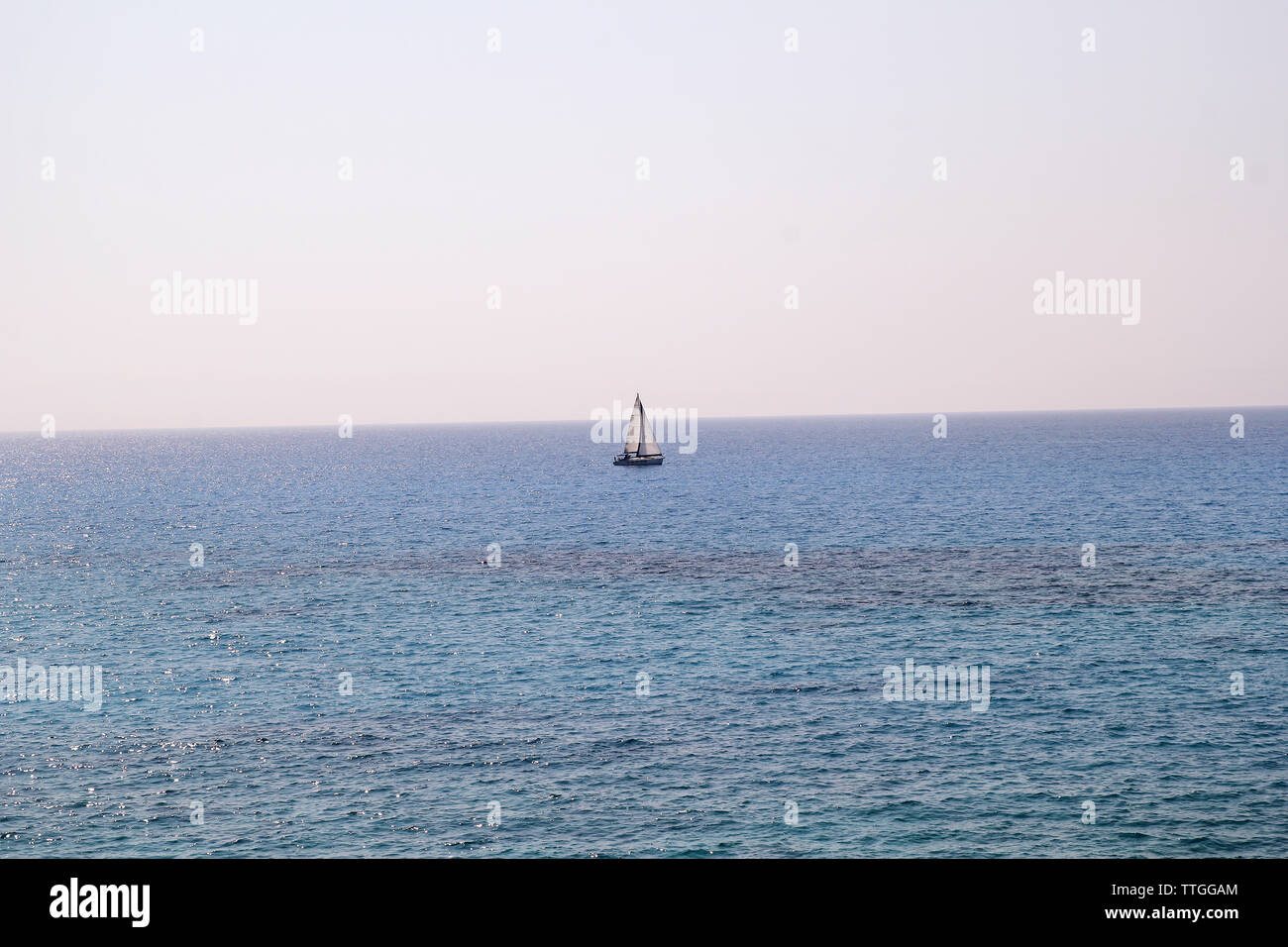 Einsames Schiff, Segelboot auf offener See. Ruhiges Meer ermöglicht beste Segeln in friedliche Szene. Kleines Segelboot auf das türkisfarbene Meer. Schöne Aussicht. Stockfoto