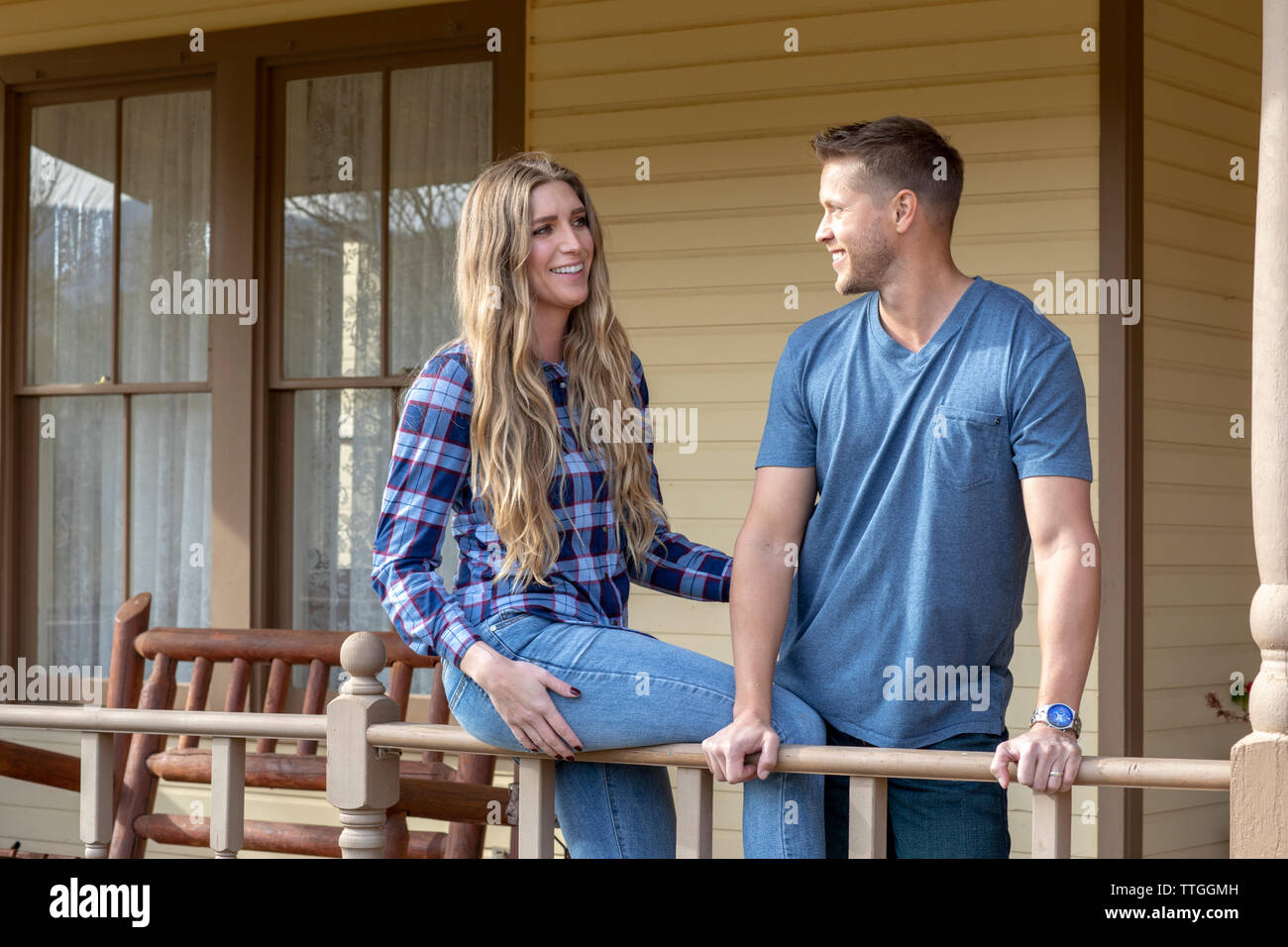 Western Wear junges Paar auf der Veranda des Hauses lächelnd Stockfoto
