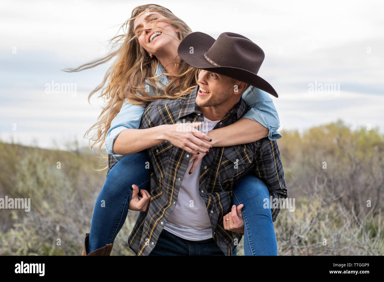 Western Wear junge Paar beim Huckepack Fahrt auf der Ranch Stockfoto