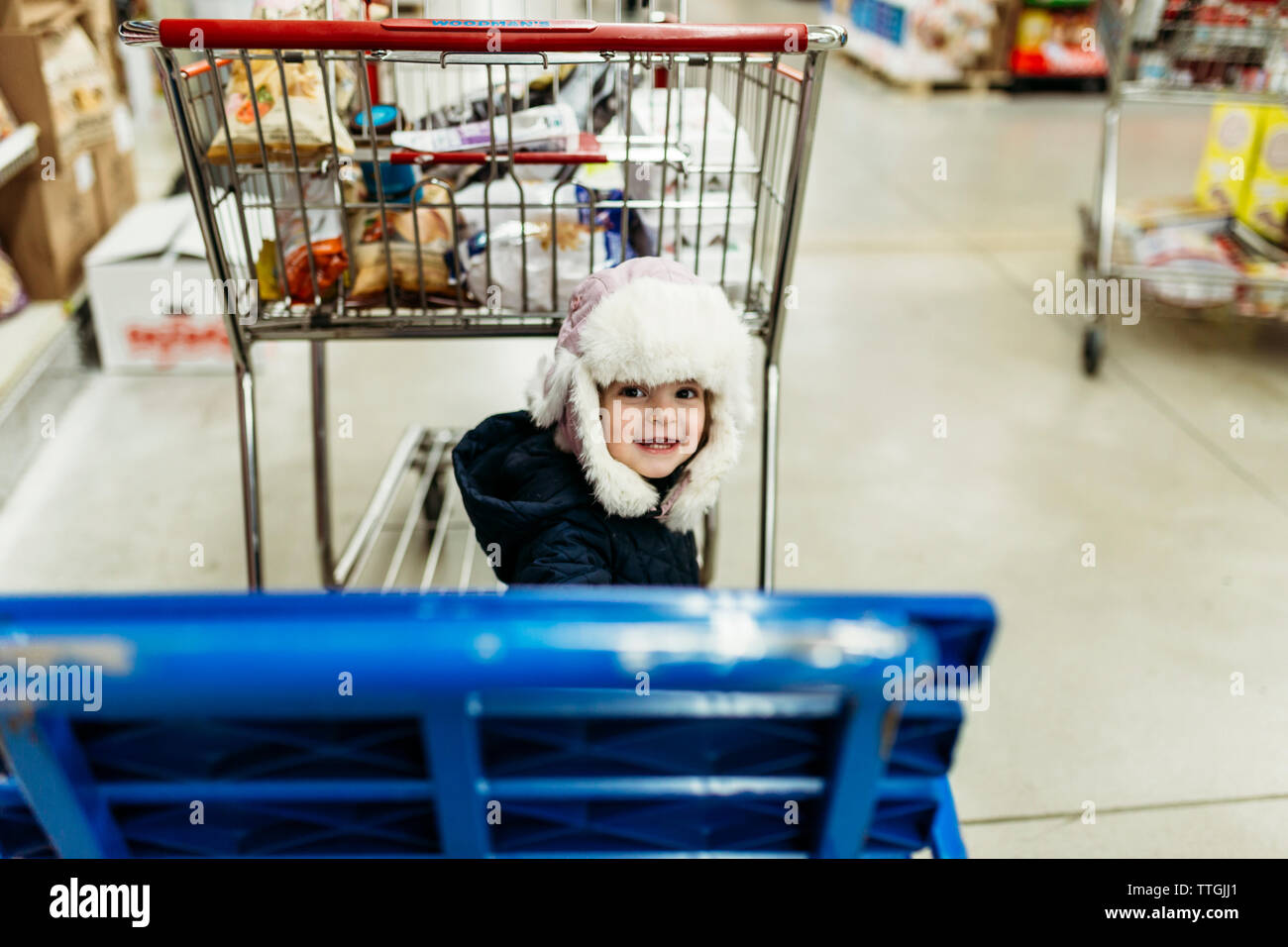 Hohen winkel Portrait von nettes Mädchen mit Einkaufswagen im Supermarkt Stockfoto