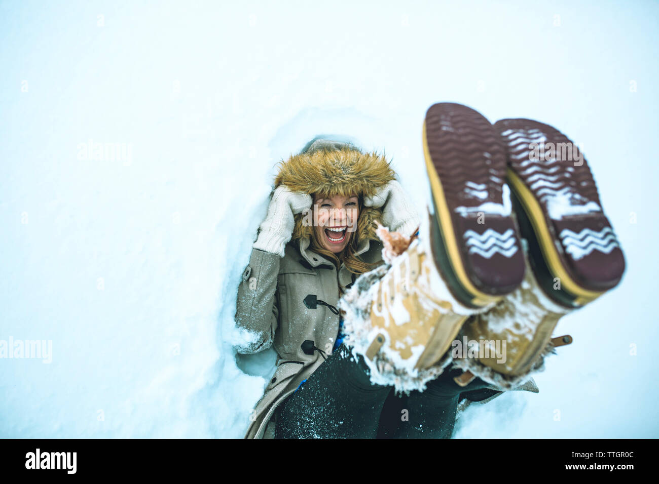 Erhöhte Ansicht der Frau liegt im Schnee auf Feld Stockfoto