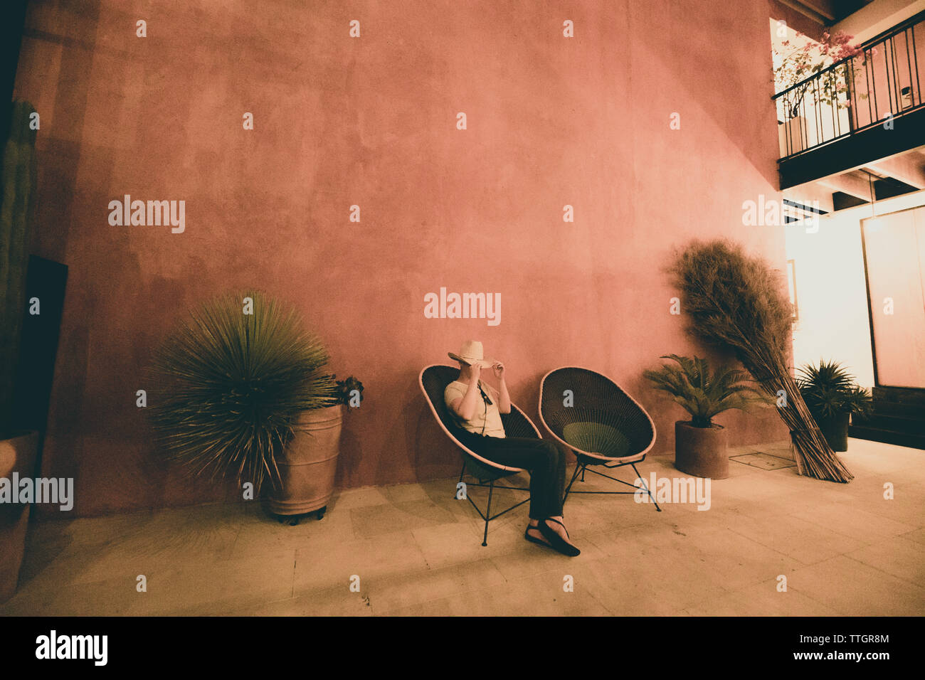 Dame sitzt im Sessel und blendet von der Kamera in der modernen Lobby Stockfoto