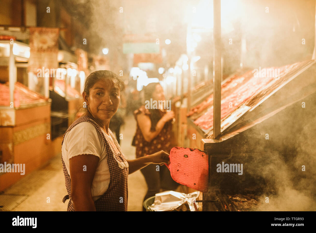 Mexikanische Frau Grillen von Fleisch an ihrem Oaxaca Garküche Stockfoto