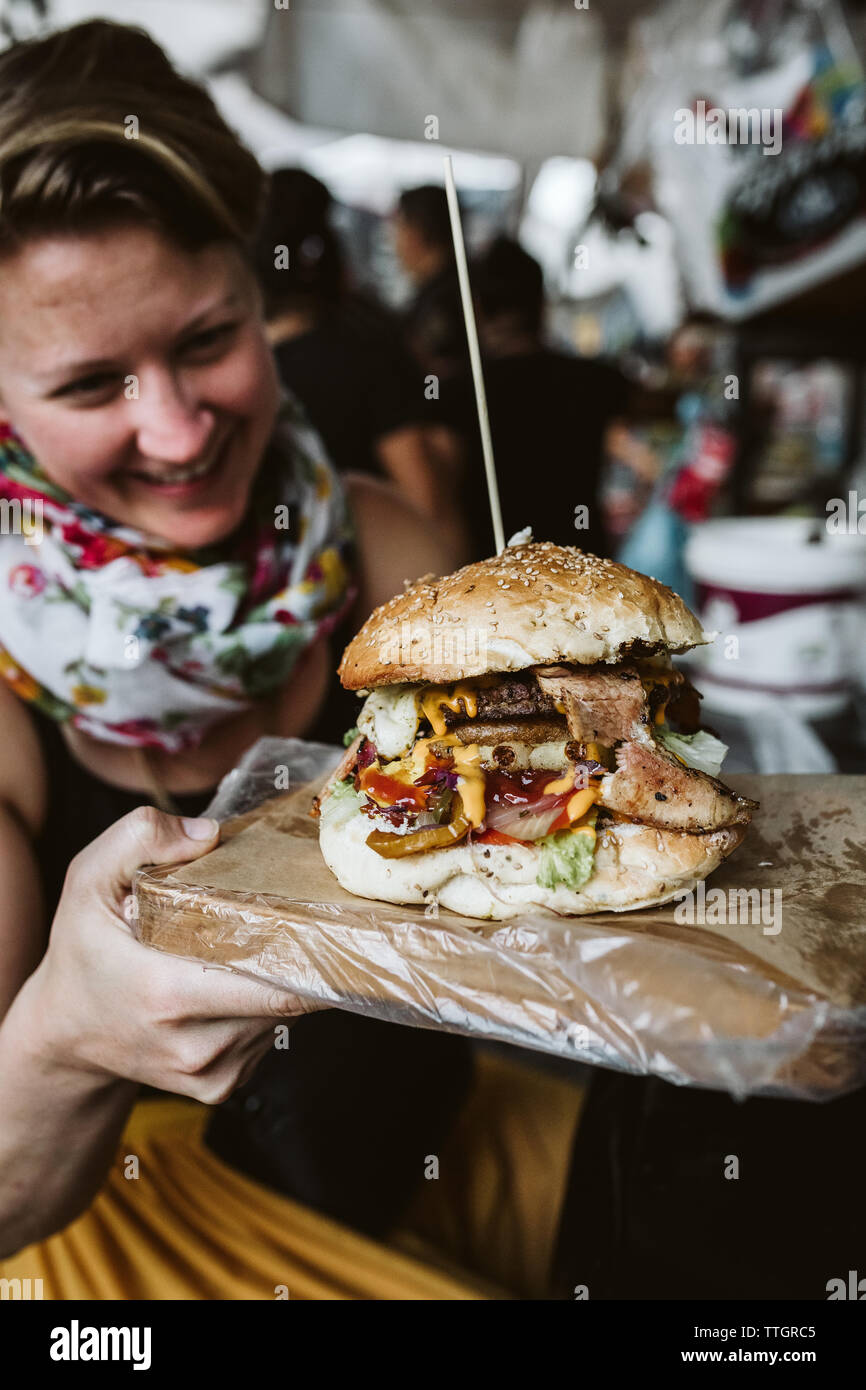 Details einer besten Cheeseburger während junge Frau sieht es Stockfoto