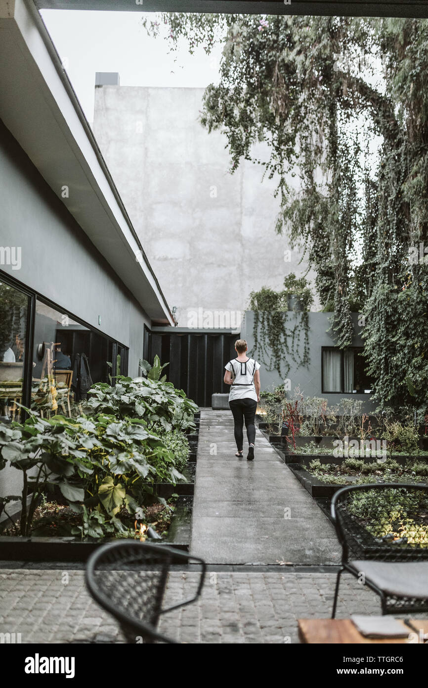 Frau Spaziergänge entlang der Zement Gehweg durch einen Garten an Pujol in cdmx Stockfoto