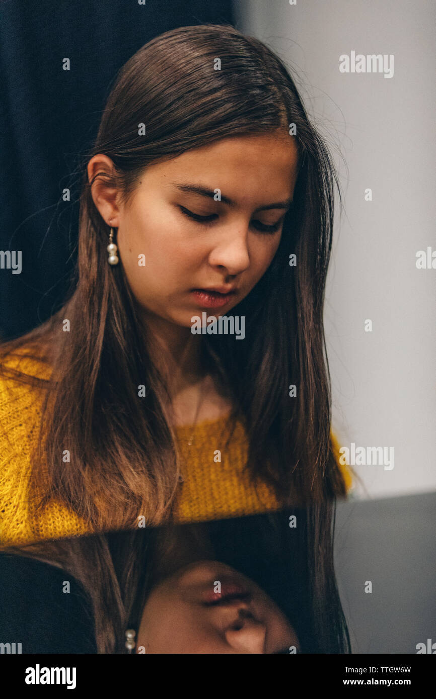 Junge Frau auf dem Klavier zu spielen. Ihr Spiegelbild in Schwarz piano Oberfläche. Stockfoto