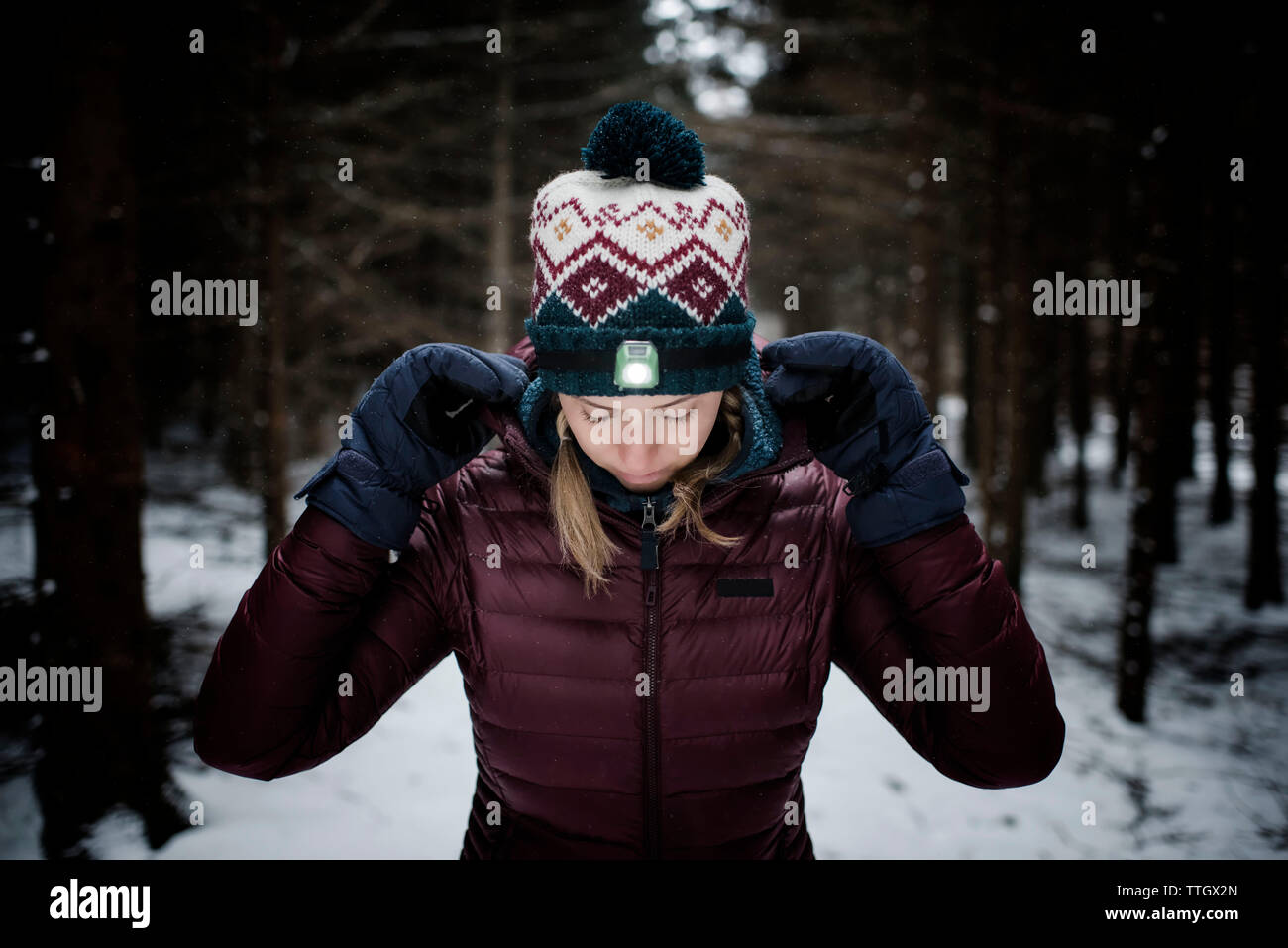Frau mit Stirnlampe und kaltem Wetter Gang im Wald im Schnee Stockfoto