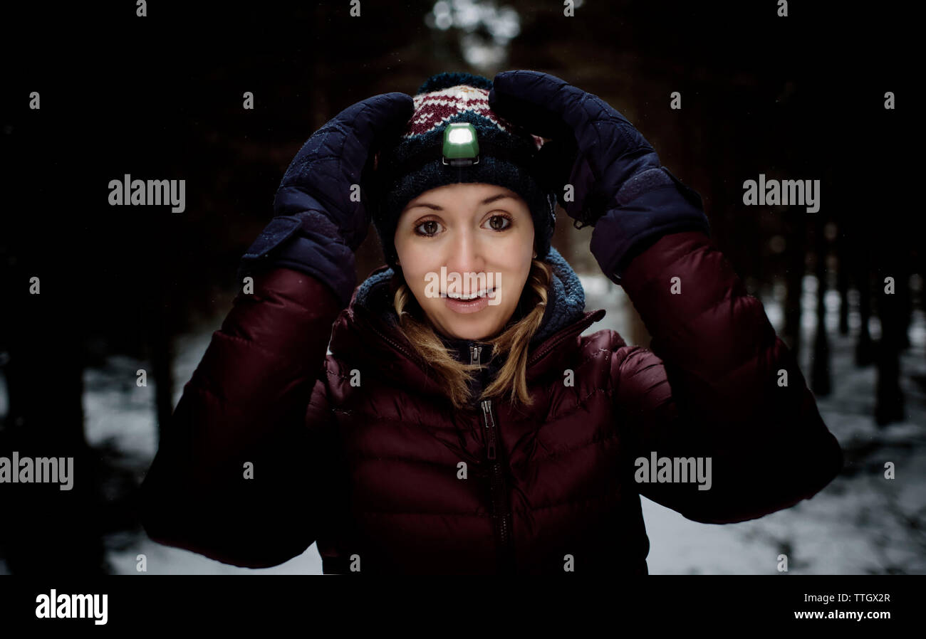Lächelnde Frau mit Stirnlampe auf Winter Gang und in den Wald Schnee Stockfoto