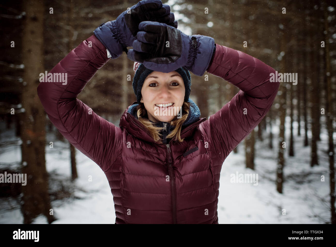 Blonde Frau im Wald lächelnd in den kalten Schnee im Freien Stockfoto