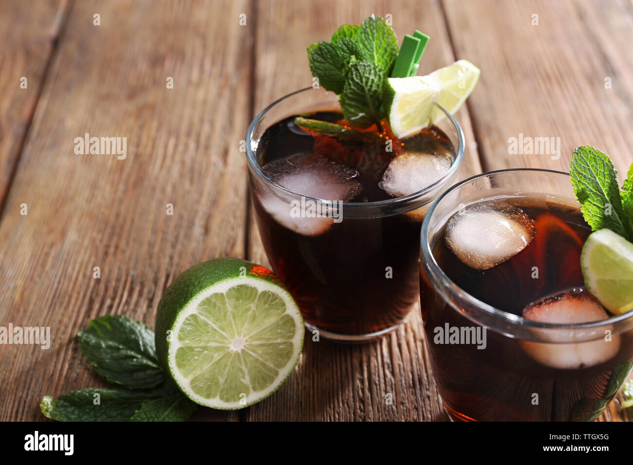 Zwei Gläser Cola mit Eis, Minze und Limette auf hölzernen Tisch Hintergrund Stockfoto