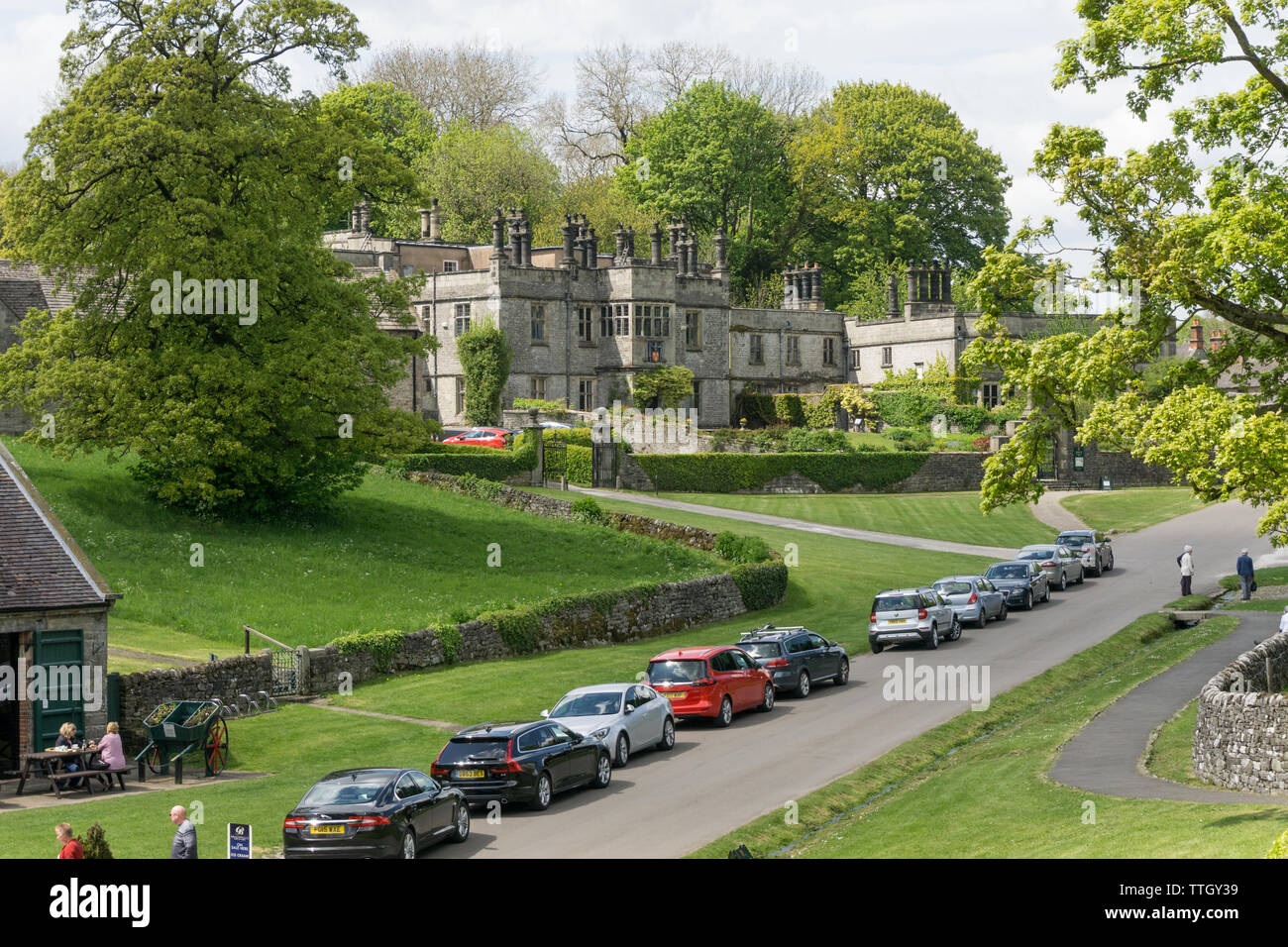 Die Hauptstraße in dem hübschen Dorf Tissington, Peak District, UK; mit Tissington Halle im Hintergrund. Stockfoto