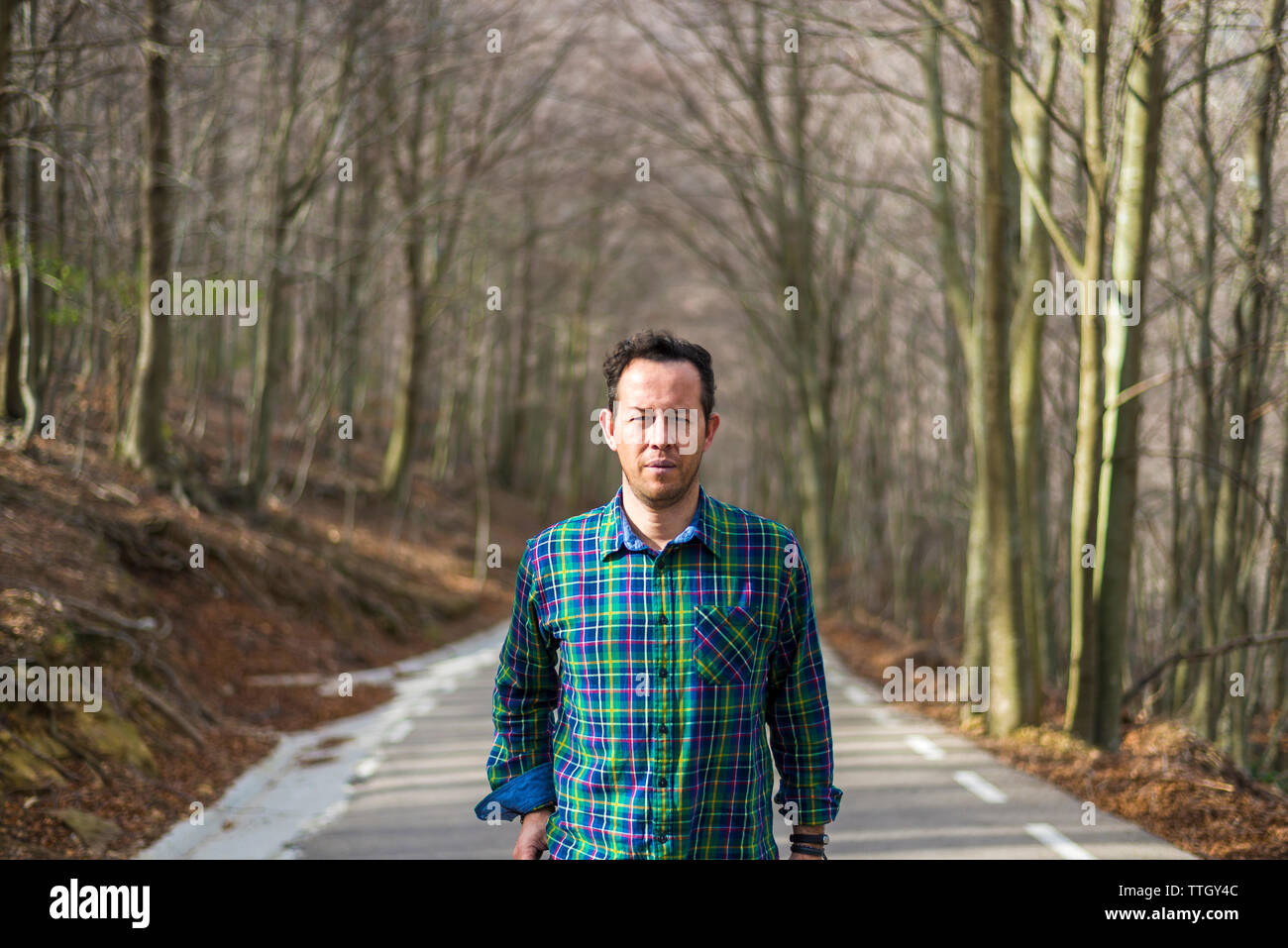 Vorderansicht eines Mannes auf der Suche Kamera, stehend auf die ländliche Straße im Herbst Stockfoto