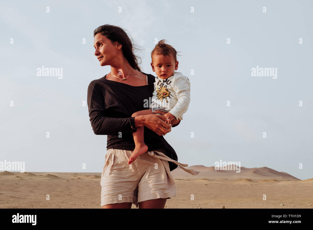 Porträt einer lateinischen Frau ihr Baby Holding in der Wüste von Peru Stockfoto