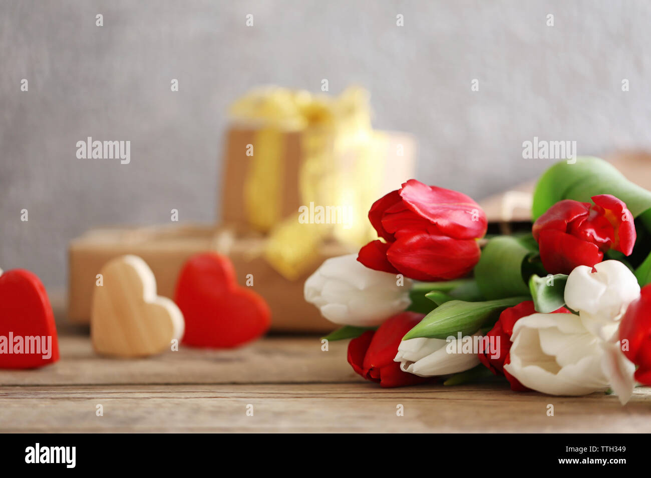 Blumenstrauß aus roten und weißen Tulpen in einer Papiertüte auf einem Holztisch, Nahaufnahme Stockfoto