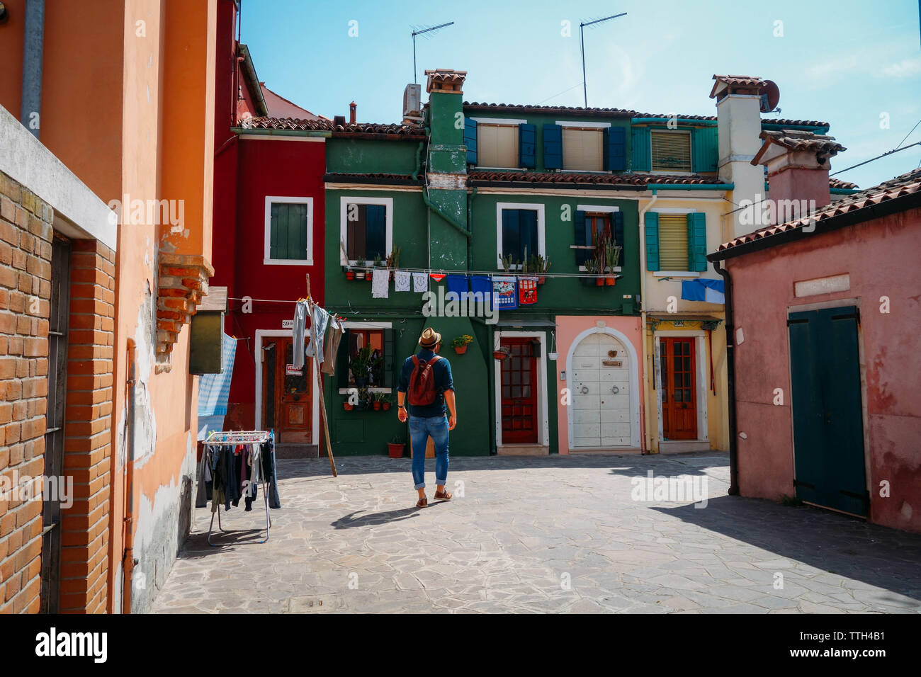 Man Walking in Burano Venedig unter bunten Häusern Stockfoto