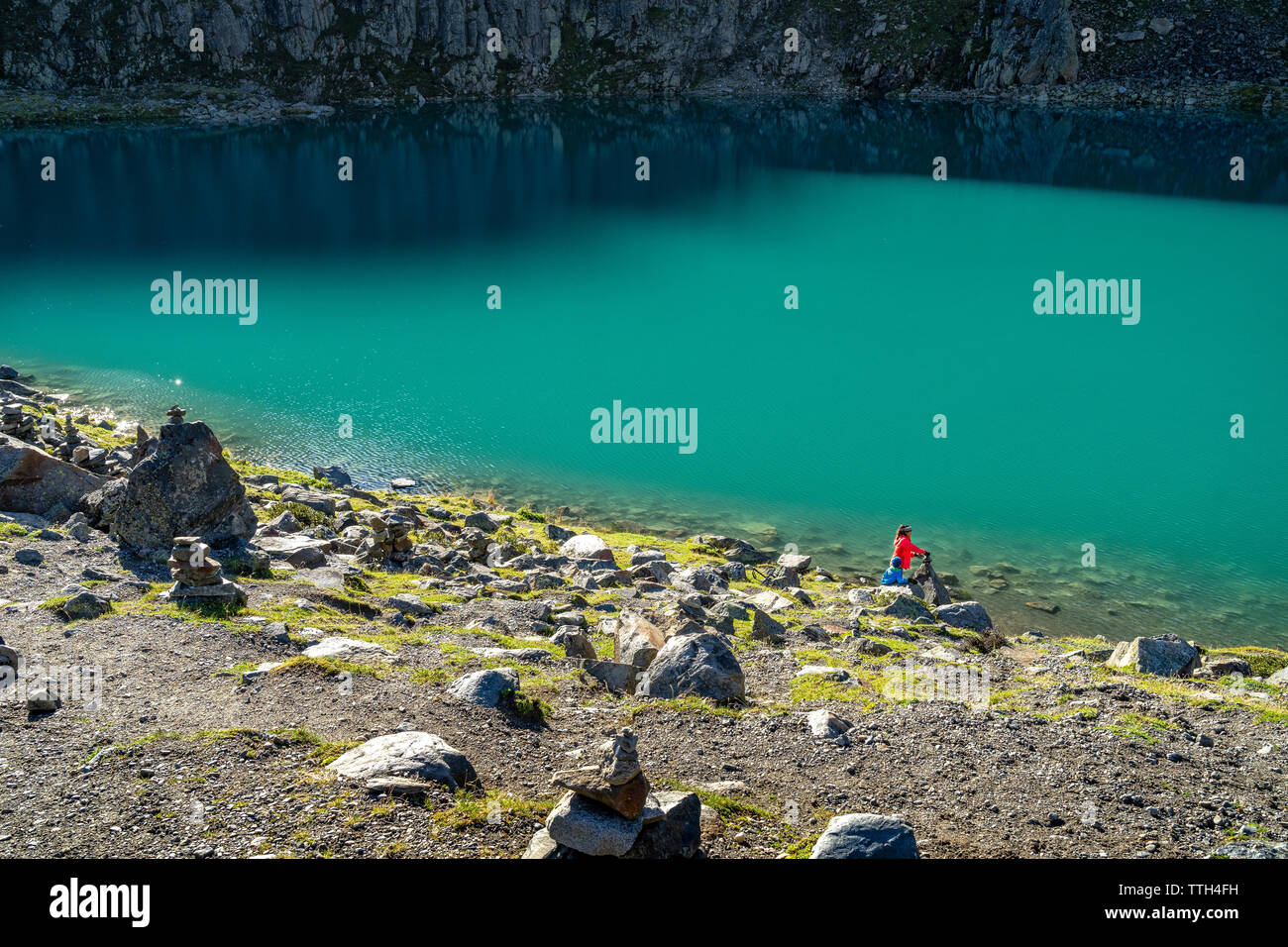 Mutter und Sohn an einem türkisfarbenen Bergsee in den Alpen an einem sonnigen Tag Stockfoto