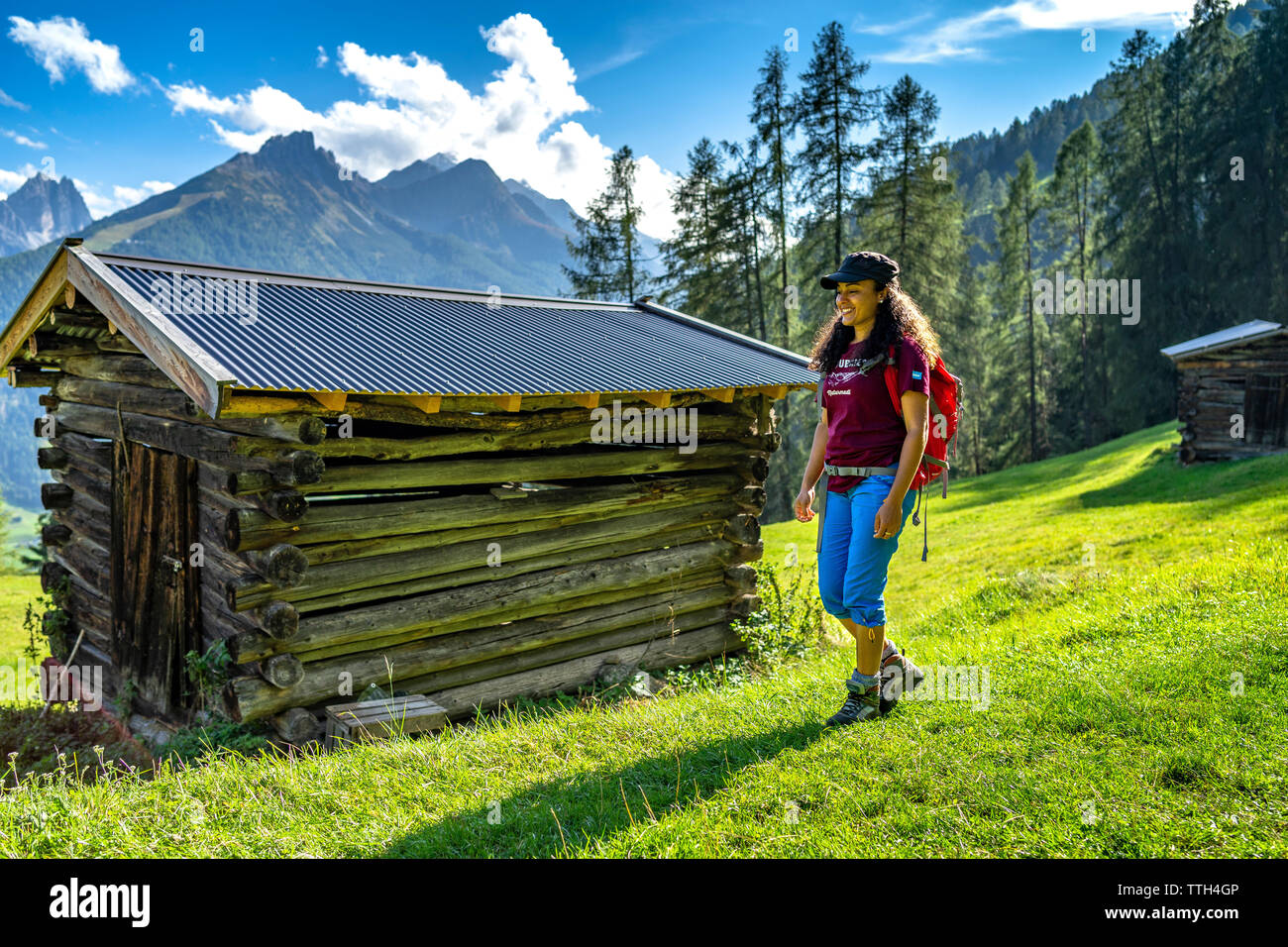 Junge Frau wandern auf einem grünen Bergwiese in den Alpen an einem sonnigen Tag Stockfoto