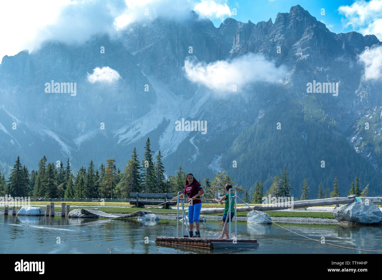 Mutter und Sohn ziehen ein Floß den Teich von einem Wasserspielplatz zu überqueren Stockfoto