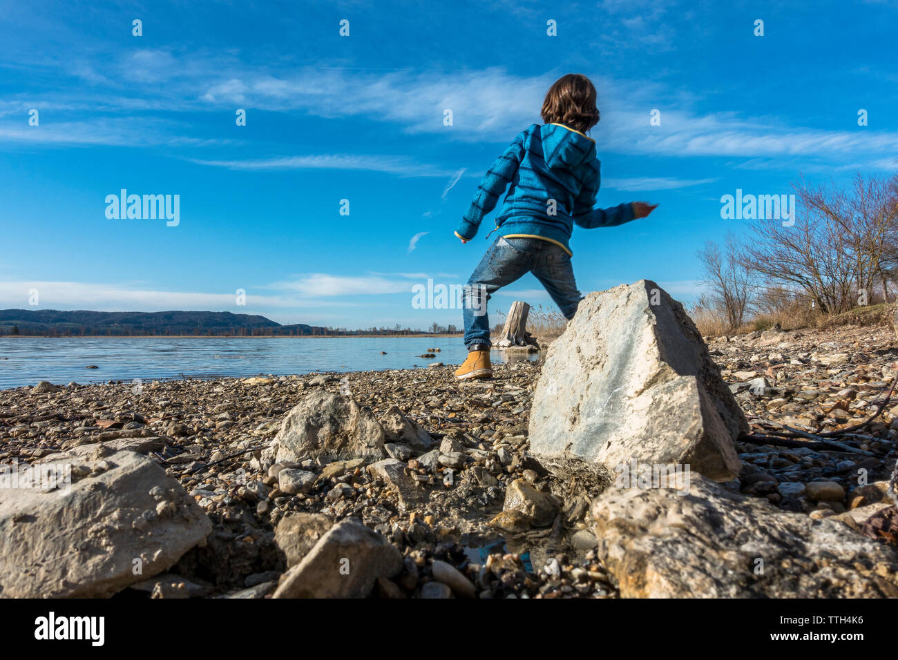 Junge flipping Steine an einem See an einem sonnigen Frühlingstag Stockfoto