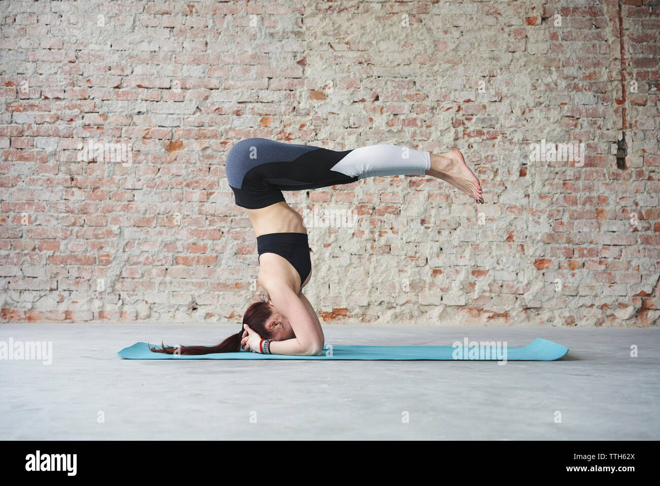 Junge weibliche im Yoga Pose von der Mauer Stockfoto