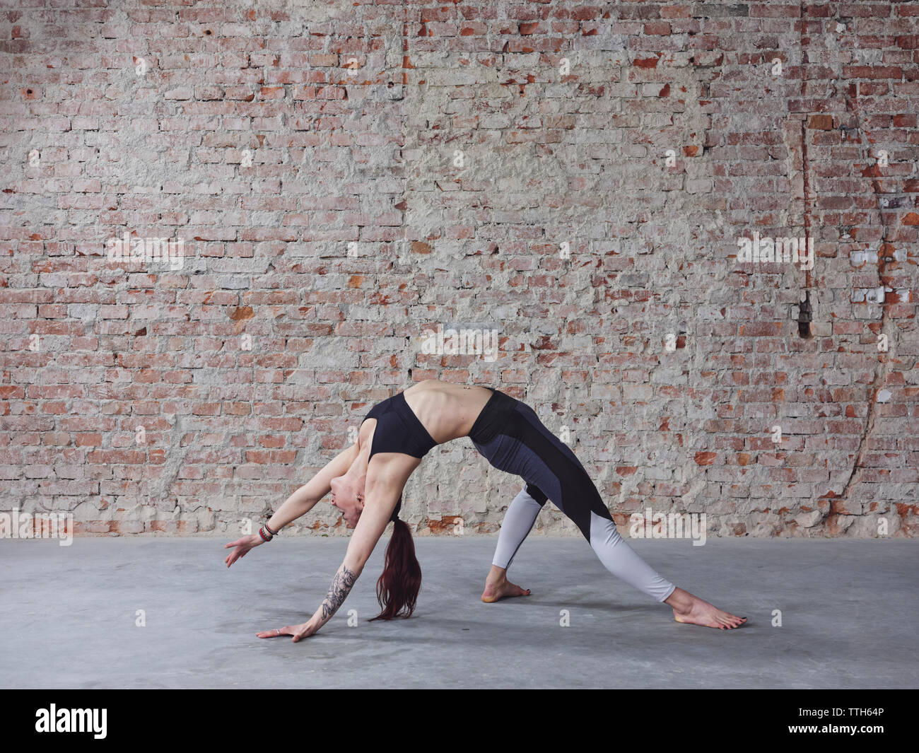 Junge weibliche im Yoga Pose von der Mauer Stockfoto