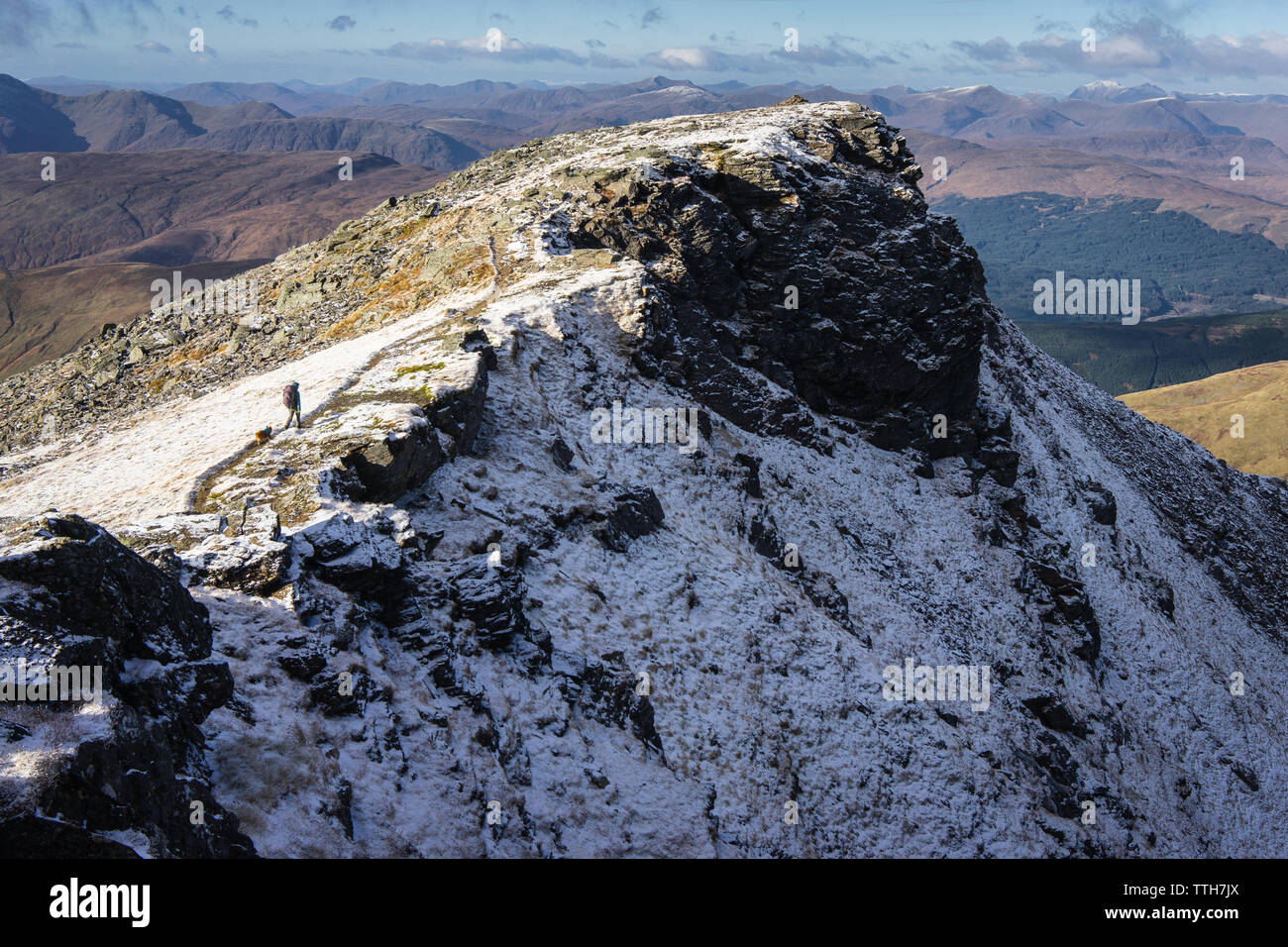 Frau und kleinen Hund entlang Pfad auf verschneiten Berg ridgeline Stockfoto