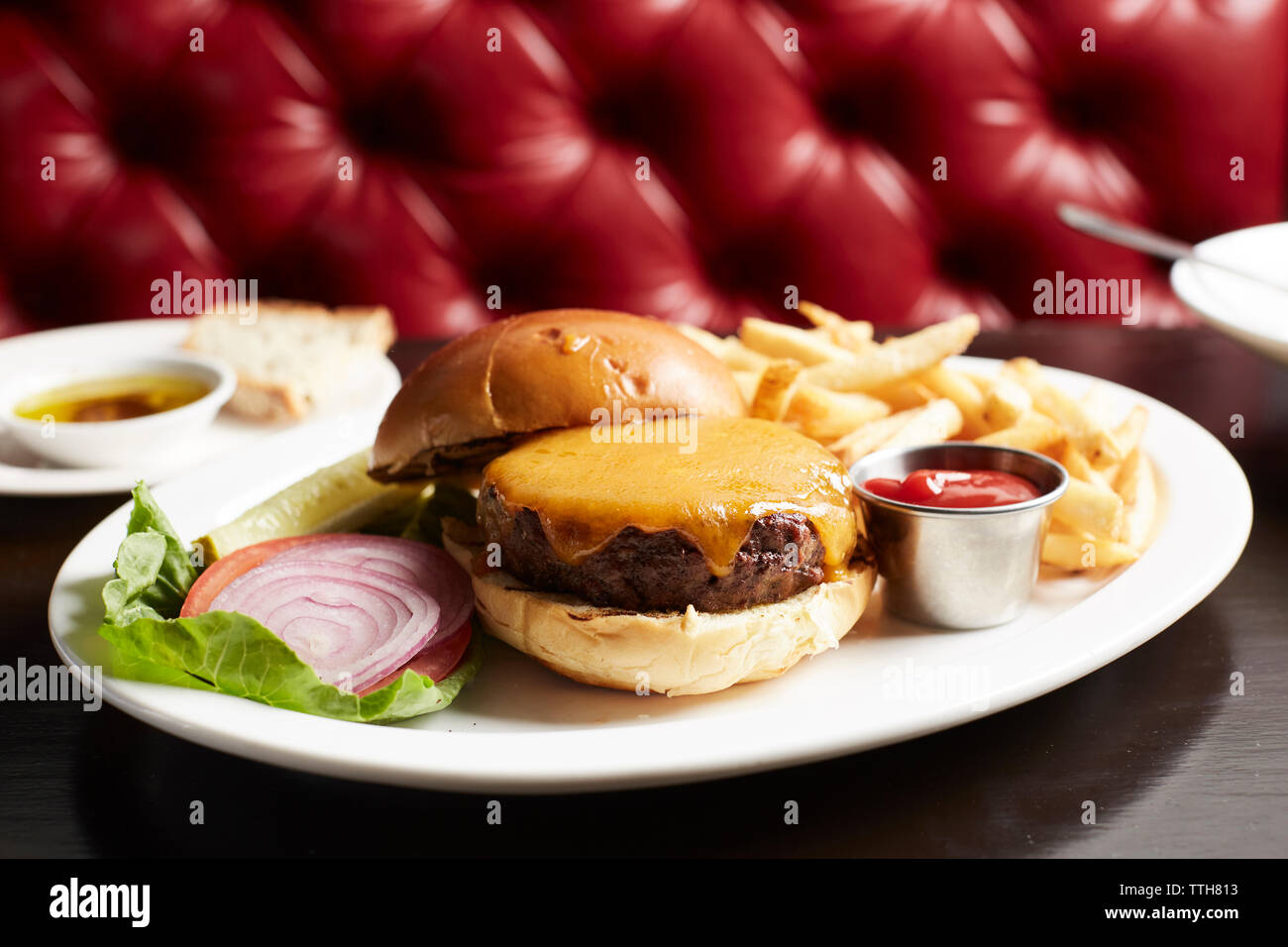 In der Nähe von Cheeseburger mit Pommes Frites auf Teller am Tisch Stockfoto
