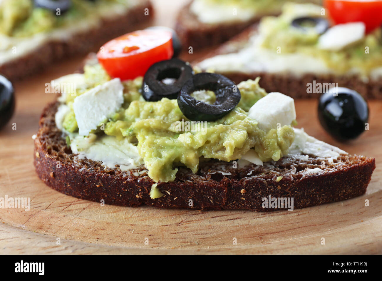 Avocado Sandwiches mit Tomaten und Oliven auf Schneidebrett Stockfoto
