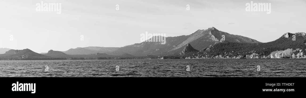 Schwarze und weiße Panorama auf den See mit den Bergen mit Wald bedeckt. Stockfoto