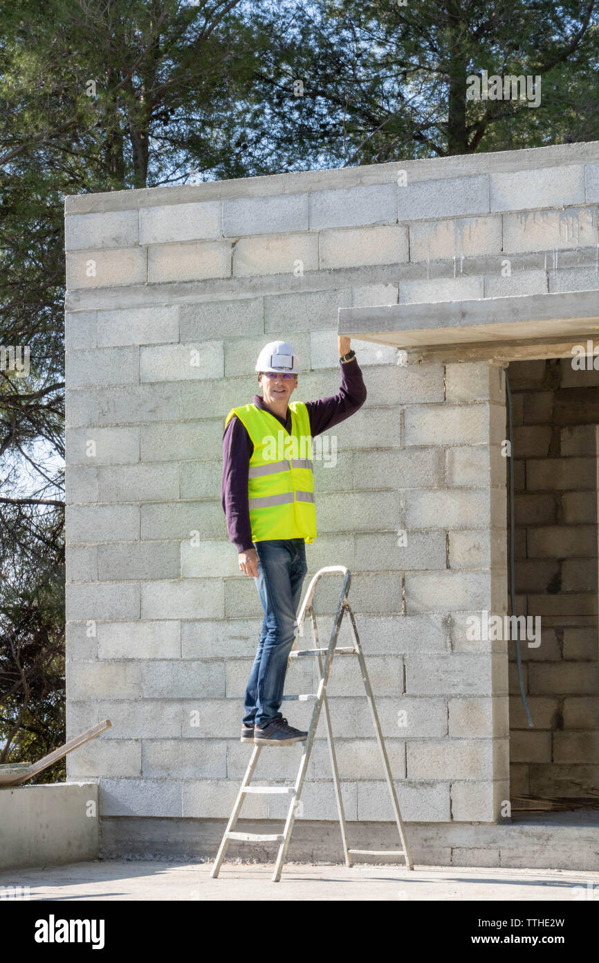 Bauleiter in Sicherheitssystemen, auf einer Leiter Haus im Bau Stockfoto