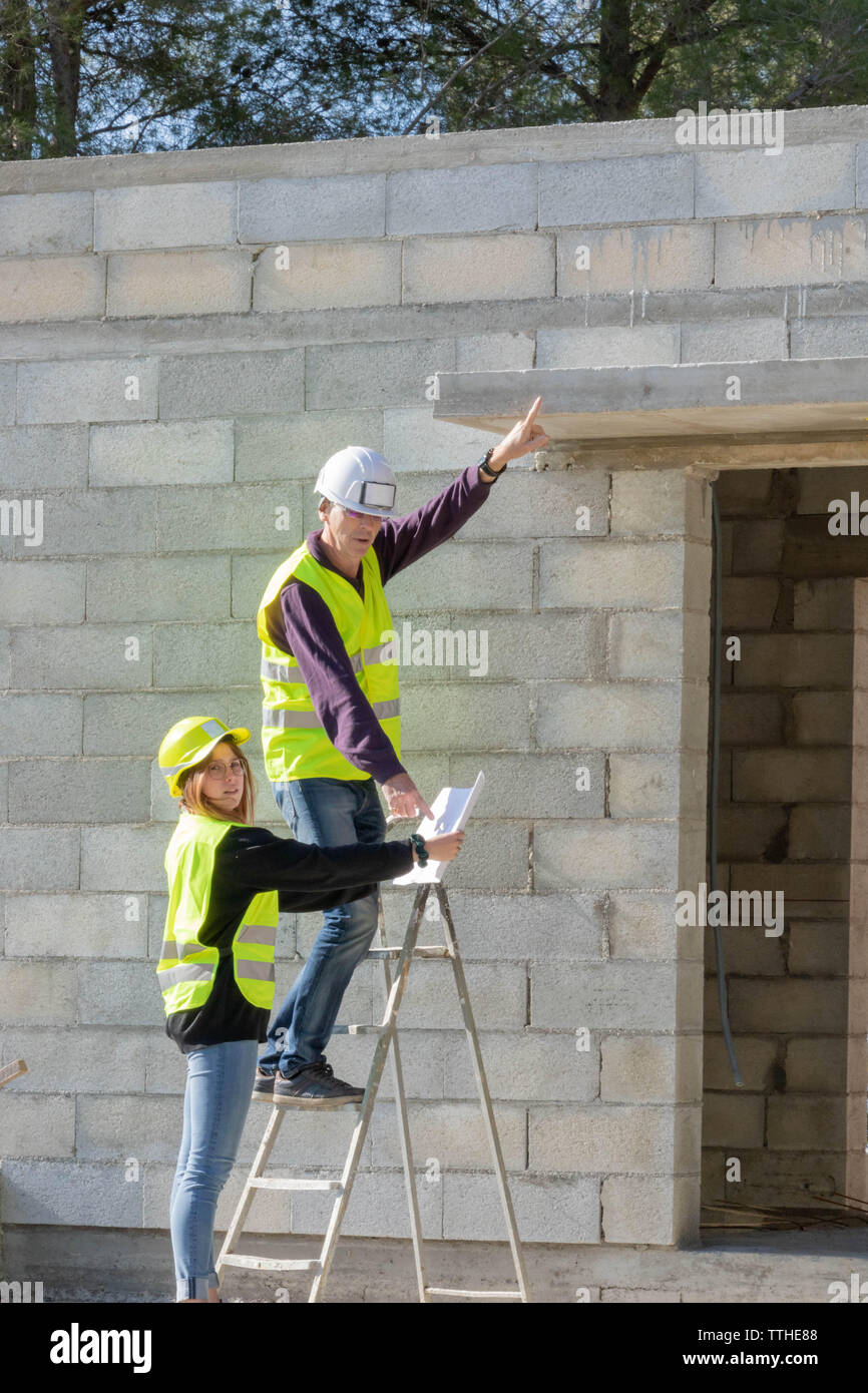 Junge auszubildende Frau mit ihrem Tutor auf einer Baustelle besuchen, Gewerke Stockfoto