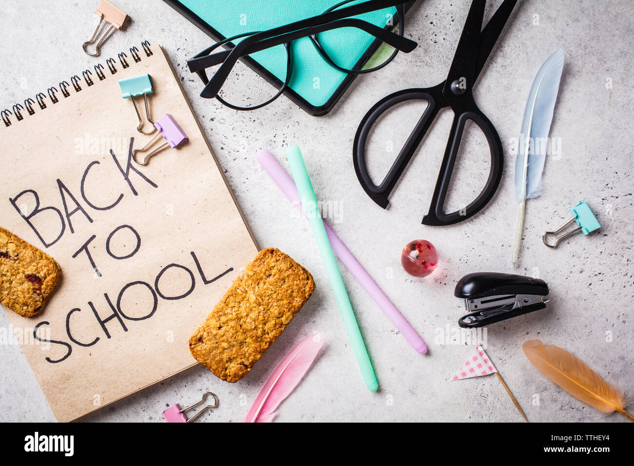 Notebook, Brillen, Kugelschreiber, Schreibwaren und Bürobedarf Objekte auf einem grauen Hintergrund, Ansicht von oben. Zurück Konzept zur Schule, Hintergrund. Stockfoto