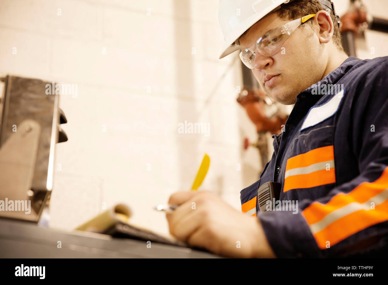 Low Angle View von ernsthaften Arbeiter schreiben in Notepad bei Recycling center Stockfoto