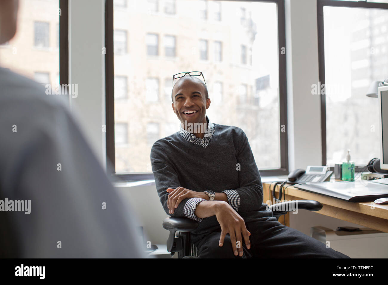 Happy Geschäftsmann an Mitarbeiter suchen, während im Büro sitzen Stockfoto