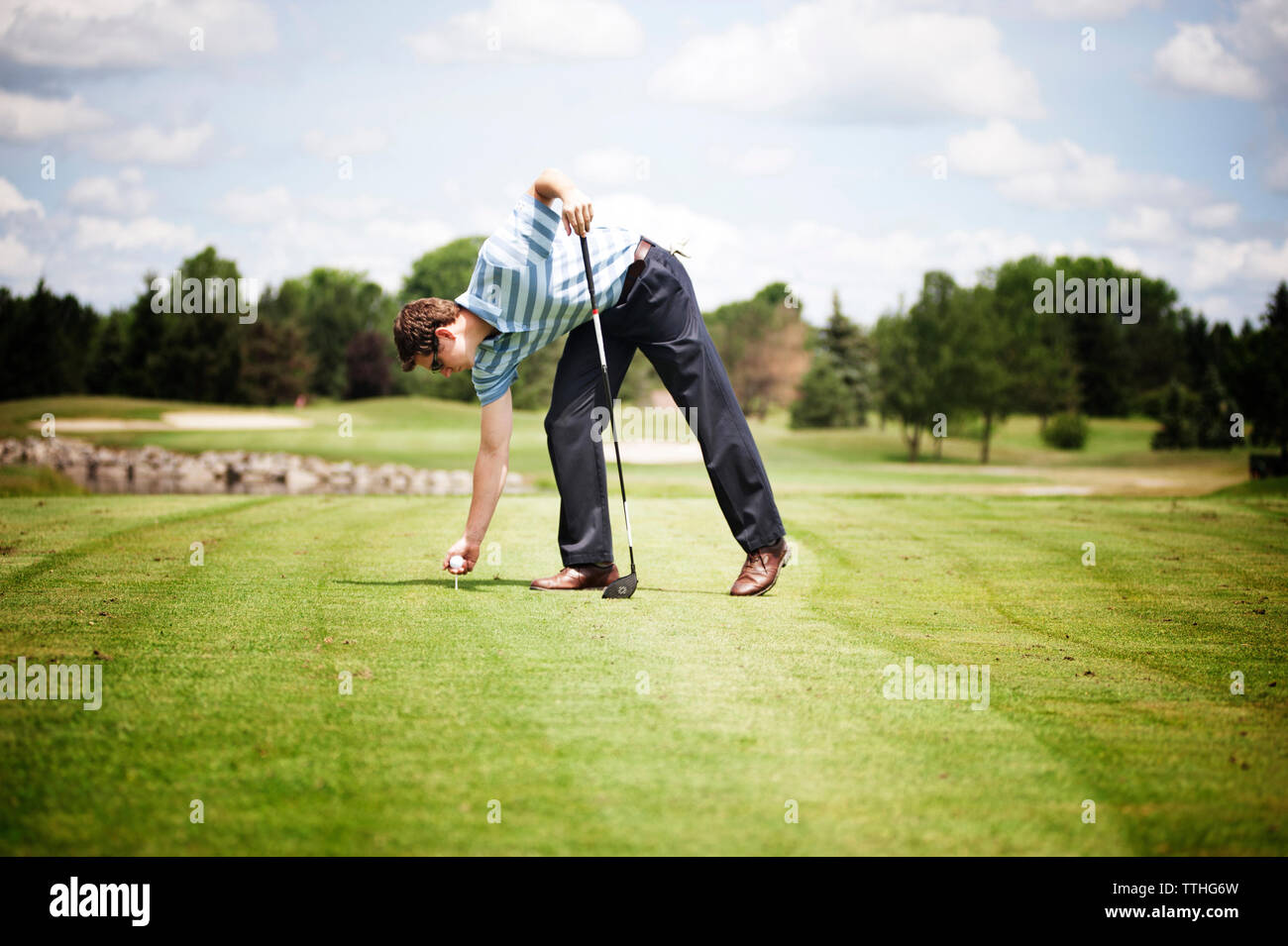 Volle Länge des Menschen die Kugel auf dem T-Stück am Golfplatz Stockfoto