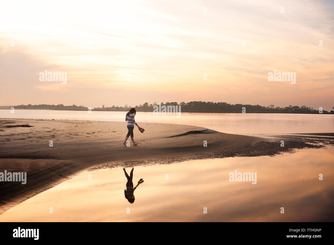 Frau gehen auf Seashore gegen Himmel bei Sonnenuntergang Stockfoto