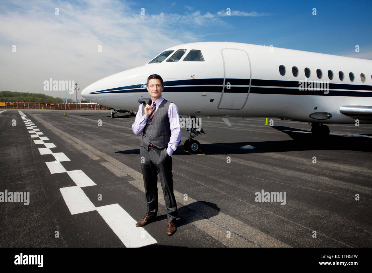 Portrait von zuversichtlich Geschäftsmann stehend gegen Corporate Jet auf Start- und Landebahn Stockfoto
