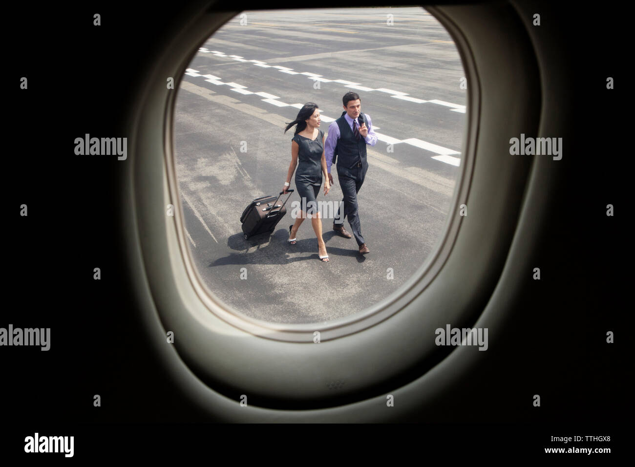 Geschäftsleute, die auf der Landebahn durch das Flugzeugfenster gesehen werden Stockfoto