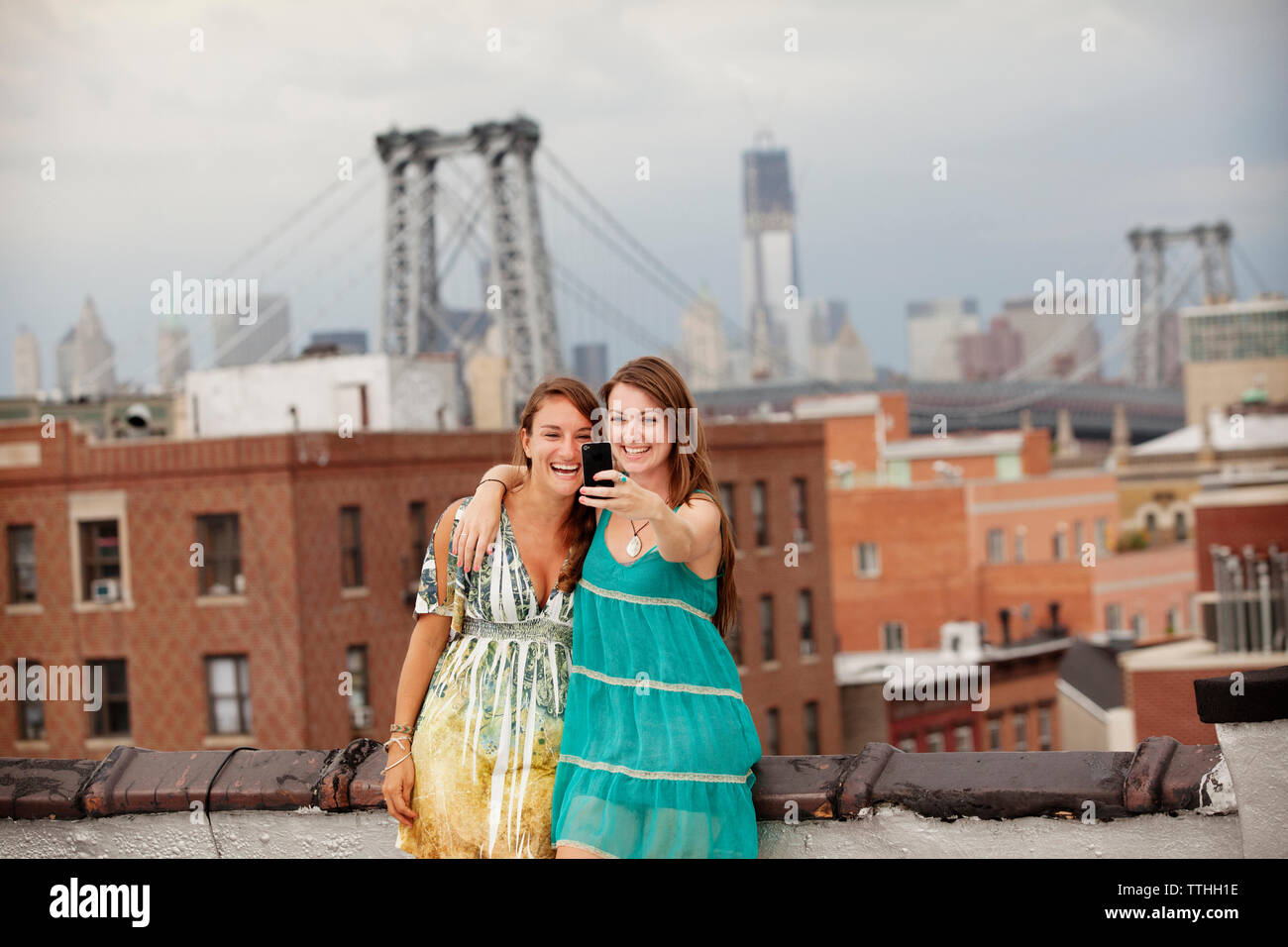 Freundliche Frauen, die selfie beim Stehen auf Gebäude Terrasse gegen Stadt Stockfoto