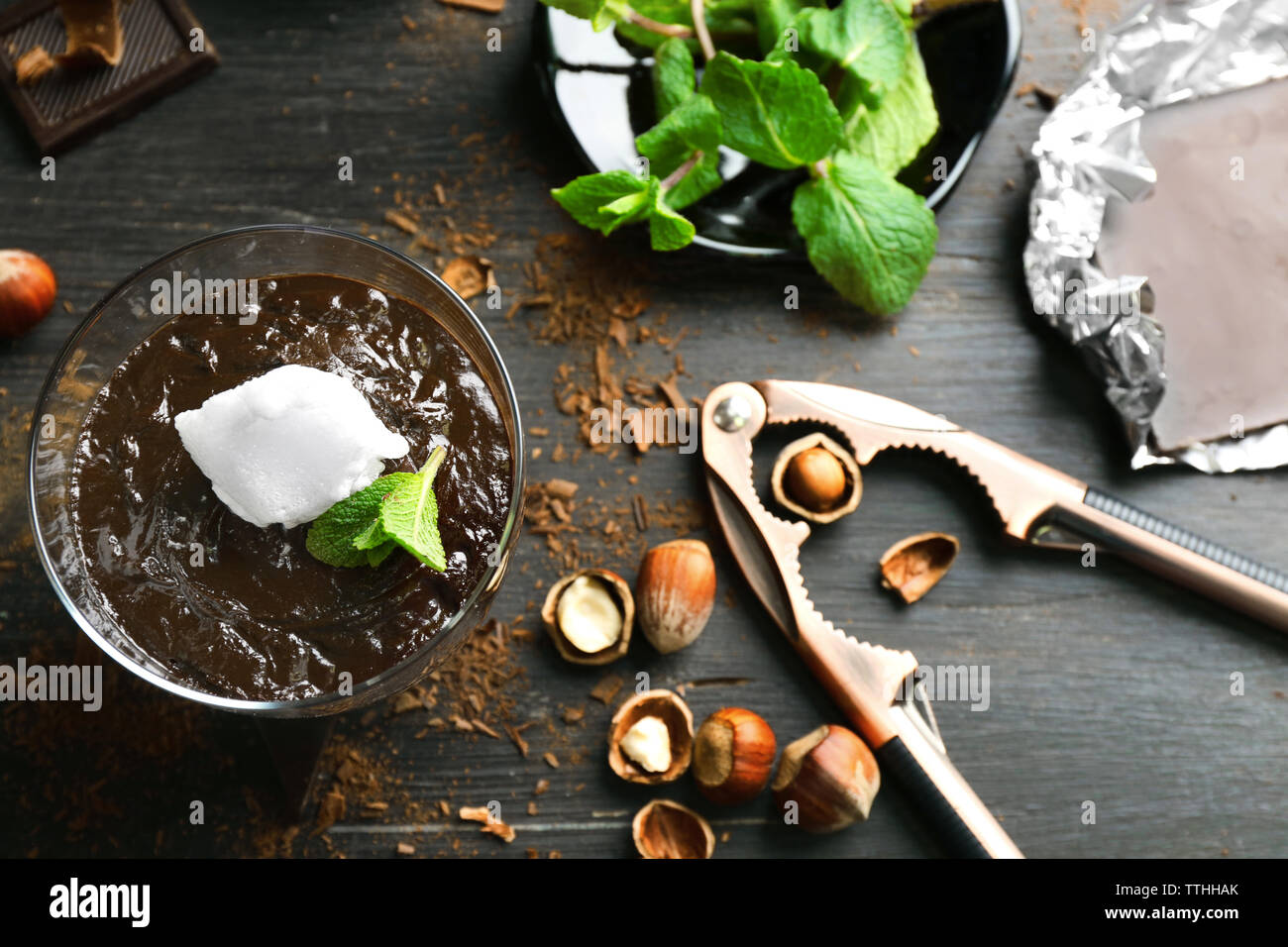 Glas Tasse Schokolade Dessert mit frischer Minze und aufgeschäumter Milch auf schwarzen Holztisch Stockfoto