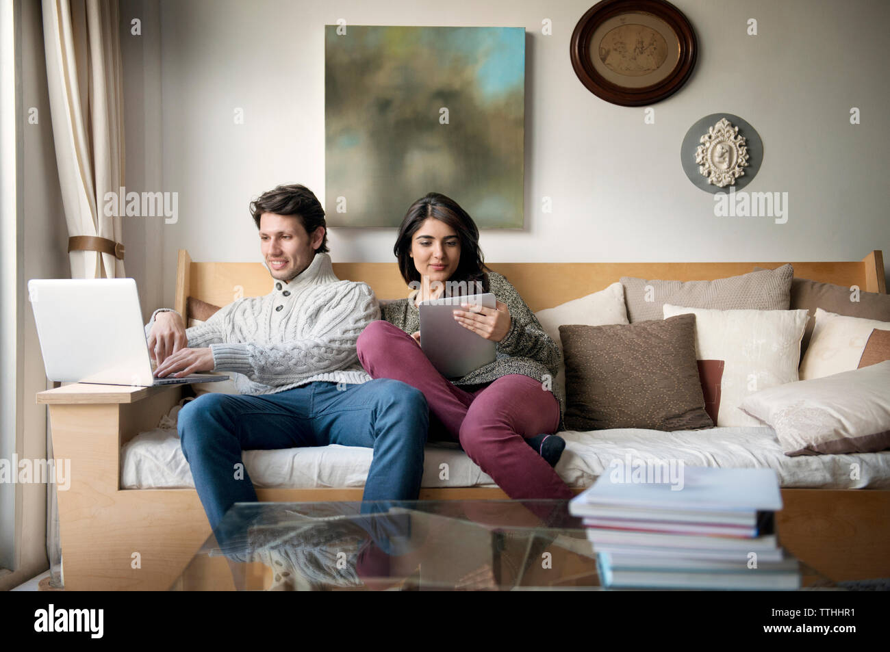 Junges Paar mit Technologien auf dem Sofa zu Hause Stockfoto