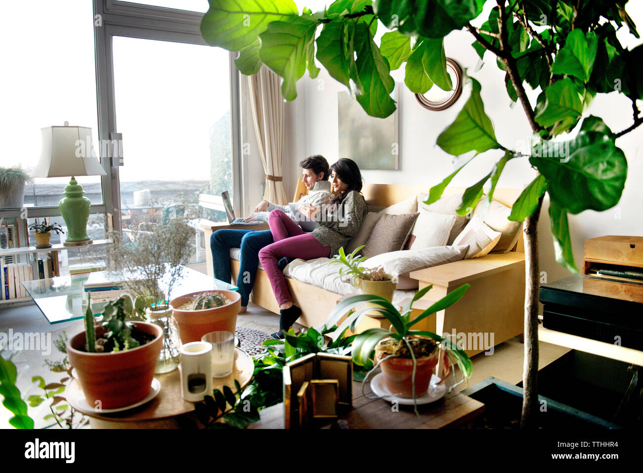 Seitenansicht des Paares mit Technologien auf dem Sofa Stockfoto