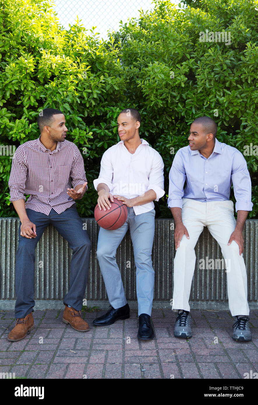 Mann, Basketball, während im Gespräch mit Freunden gegen Pflanzen Stockfoto