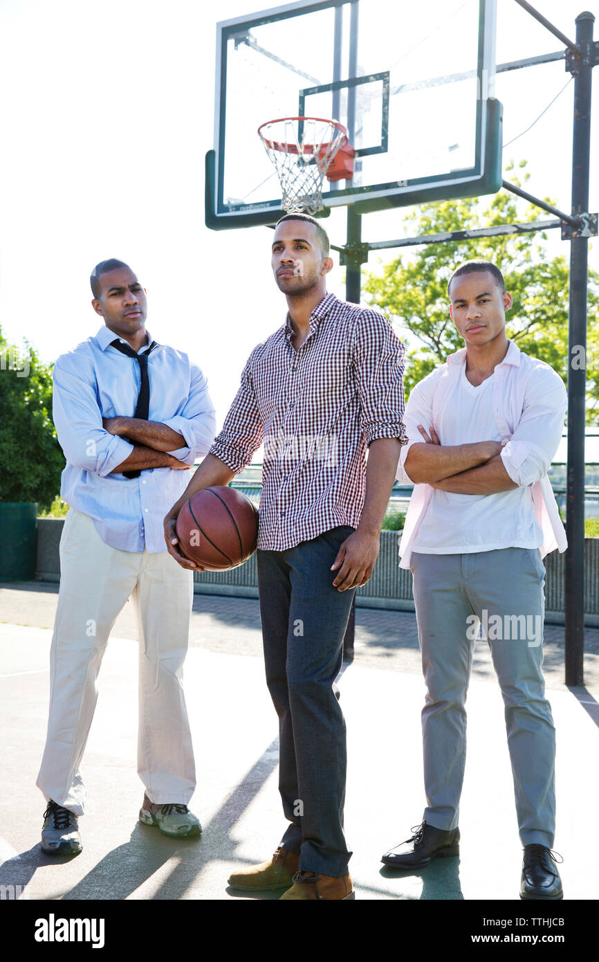 Sicher Mann mit Basketball beim Stehen mit Freunden im Hof Stockfoto