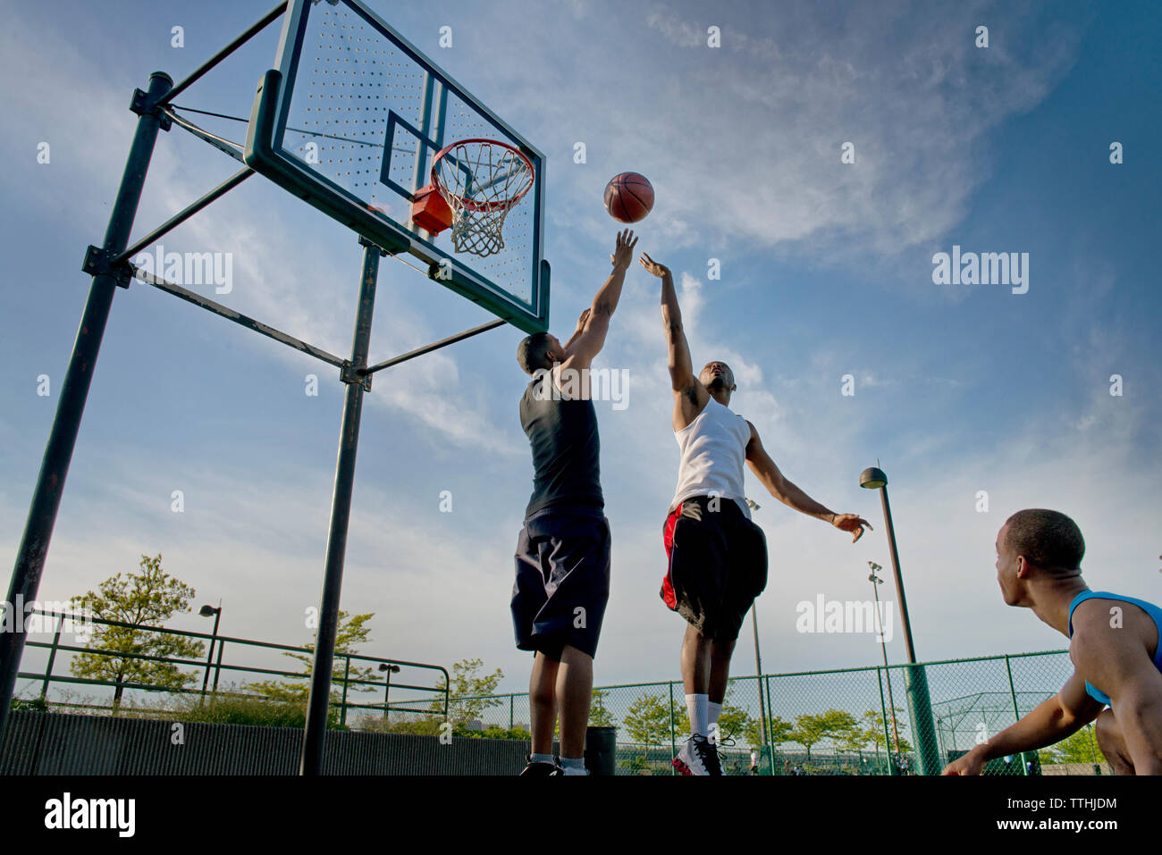 Low Angle View der Sportler Basketball spielen vor Gericht gegen Sky Stockfoto