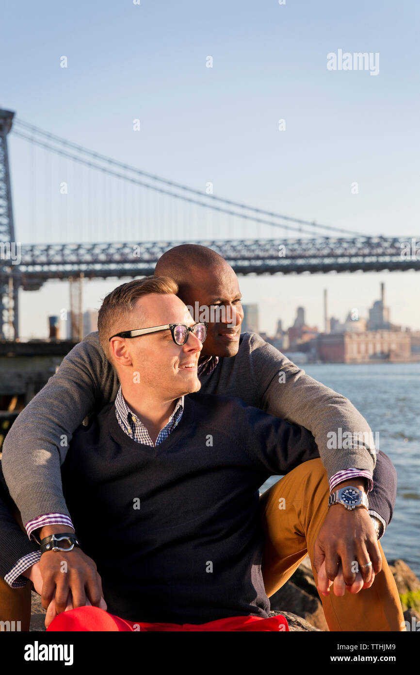 Romantische Freunde am East River, während gegen die Williamsburg Bridge sitzen Stockfoto