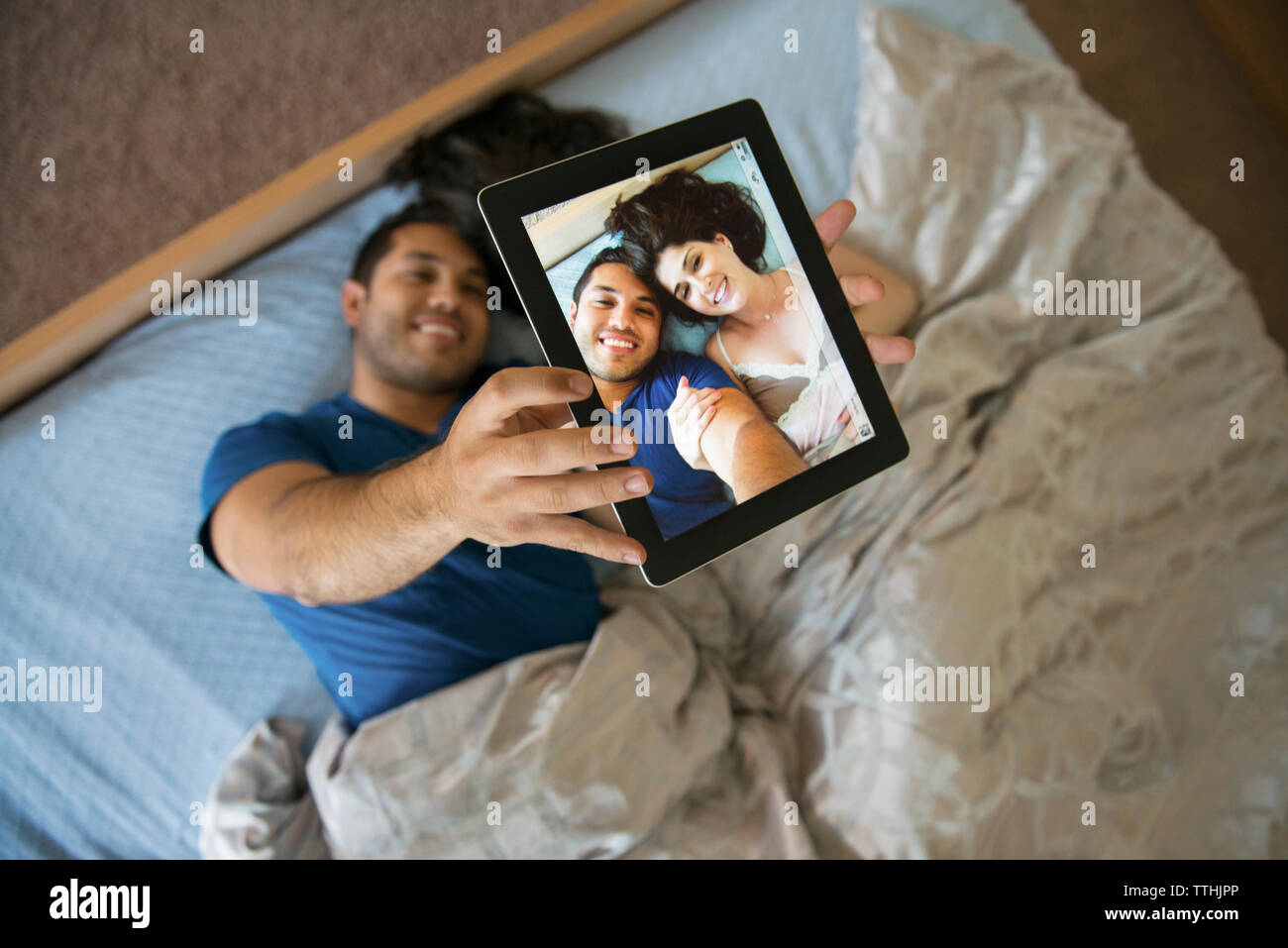 Draufsicht des glücklichen Paares unter selfie durch Tablet beim liegen auf dem Bett Stockfoto