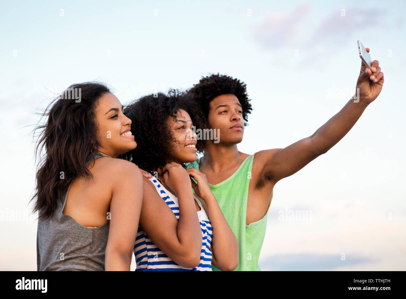 Gerne Freunde unter selfie durch Smart Phone gegen Sky Stockfoto
